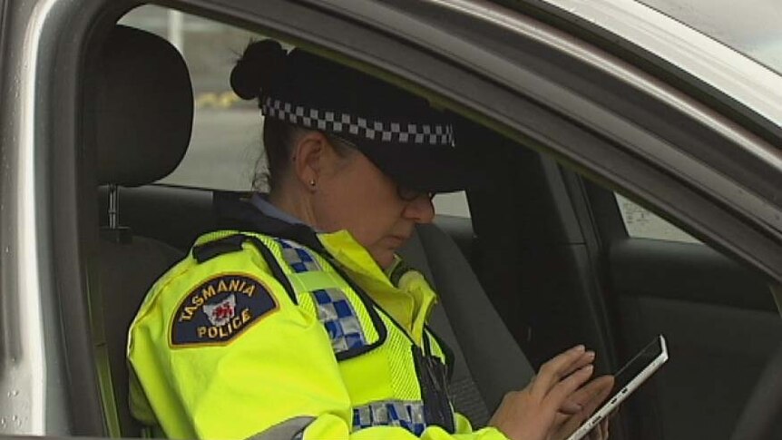 A Tasmanian police officer uses a tablet computer to issue a traffic fine.