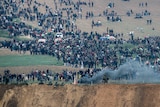Israeli soldiers are seen on one side of the fence as Palestinian protesters gather on the other.