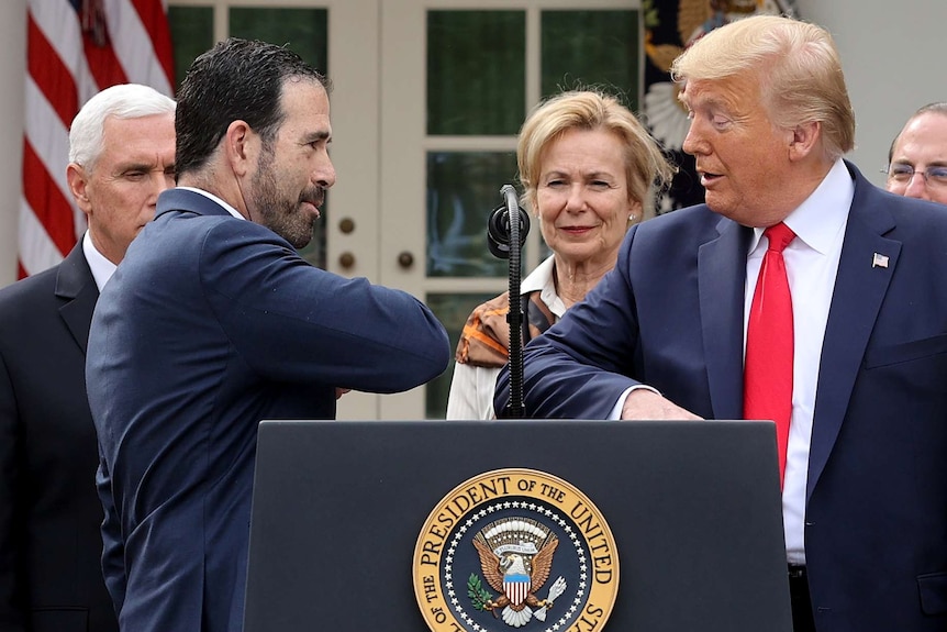 Donald Trump and Bruce Greenstein bump elbows during a press conference outside the White House