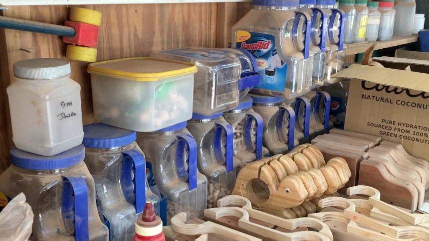 Wooden toys and containers of parts of the toys in an assembly line.