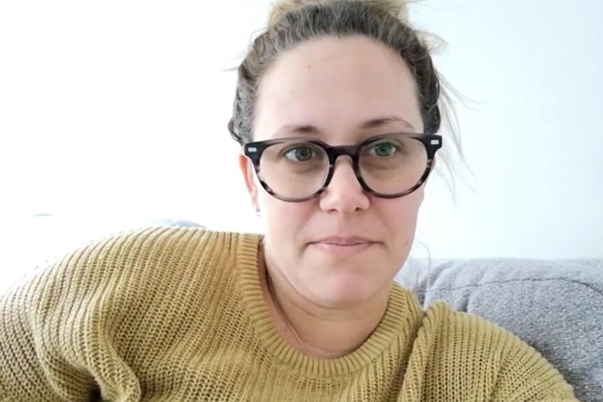 Jayde Mills wearing a yellow jumper sitting on a grey couch