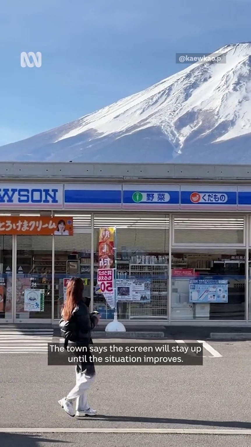 A storefront with Japanese and Roman characters sits in front of a partially cropped snow-capped mountain