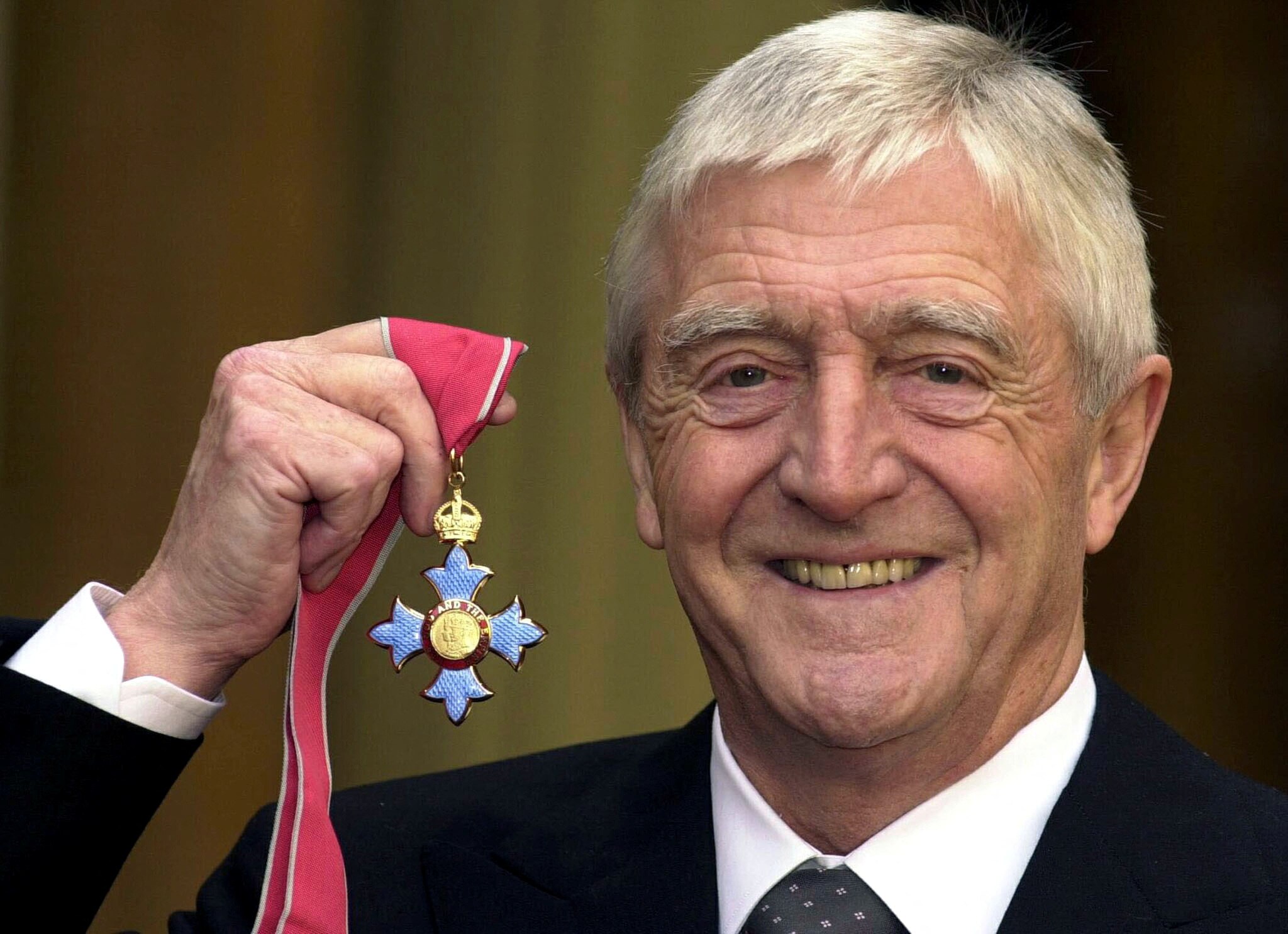 Man holds up blue medal 