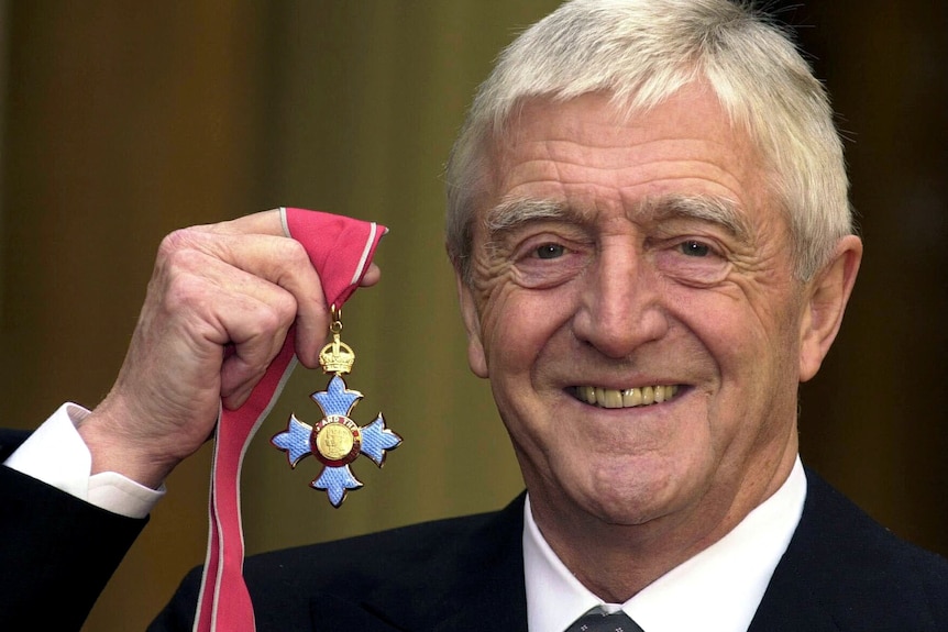 Man holds up blue medal 