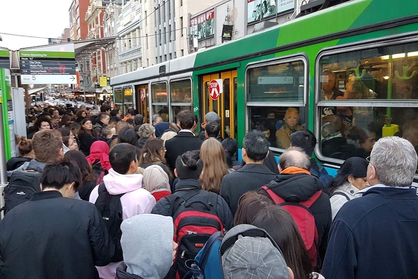 People crowd up as they try and get on a packed tram stop outside Flinders Street Station.