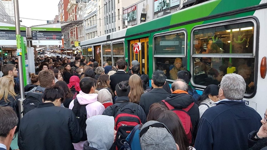People crowd up as they try and get on a packed tram stop outside Flinders Street Station.