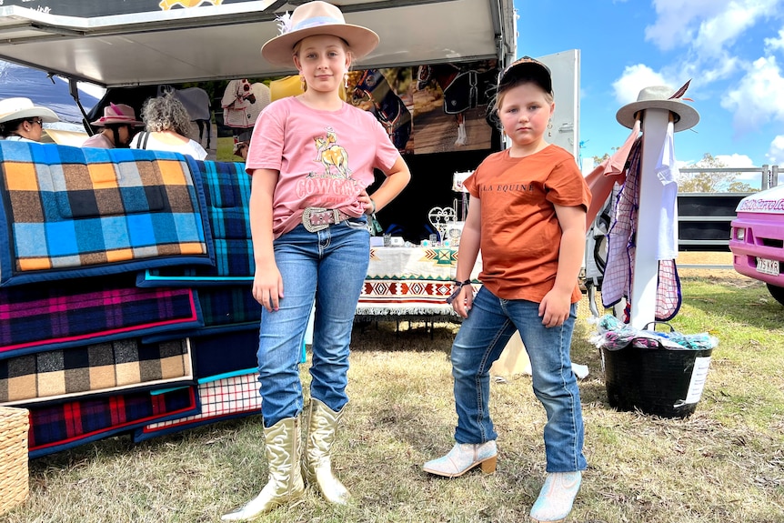 Two young girls show off their boots and pose for the camera.