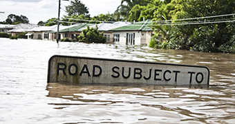 A 'road subject to flooding' sign mostly under flood waters.