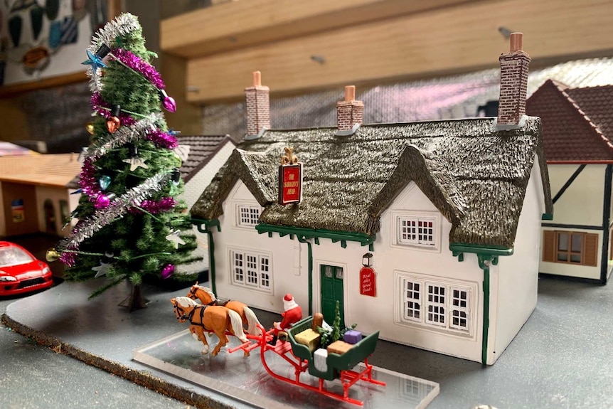 Tiny replica of pub with Christmas tree and Santa and his reindeers out front.