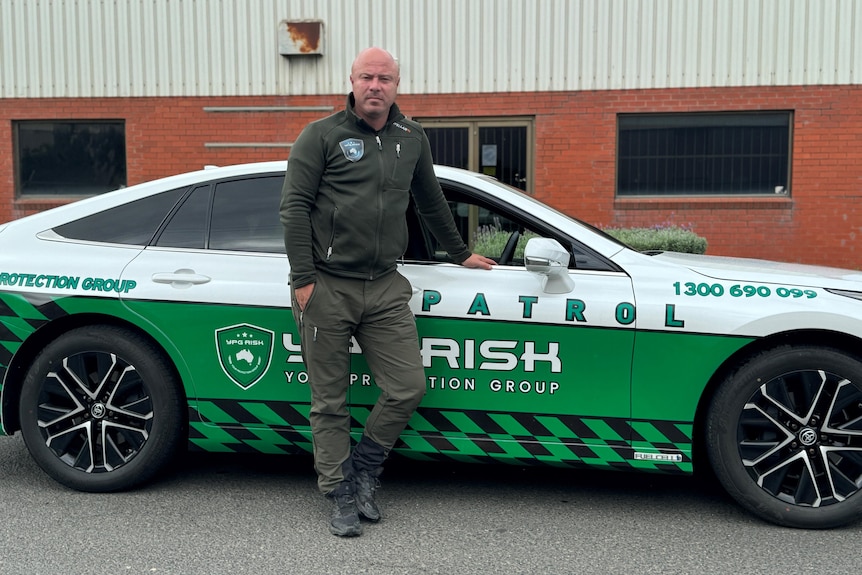 a man with a patrol car with green and white decals