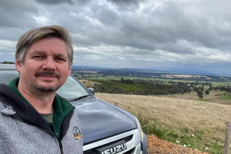 man standing in front of car and Gippsland landscape