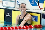 A woman in a pool looks up towards the board