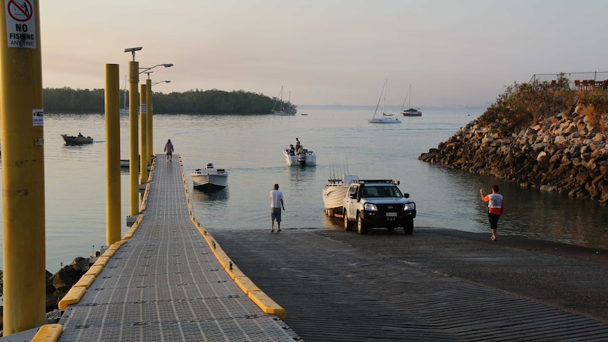 boats being launched at a ramp on a still day.