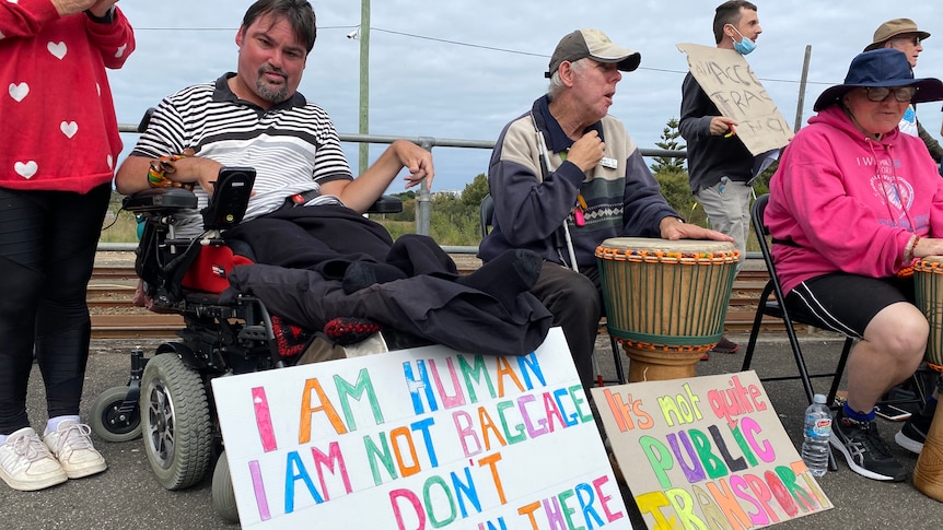 A man in a wheelchair with a sign reading "I am human" 