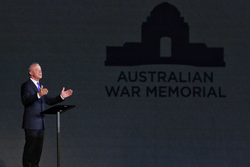 Brendan Nelson speaks at a lectern with the Australian War Memorial logo projected on a wall nearby.