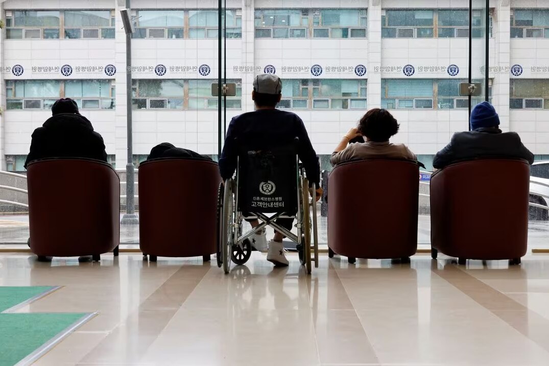 People sitting down facing a large glass window