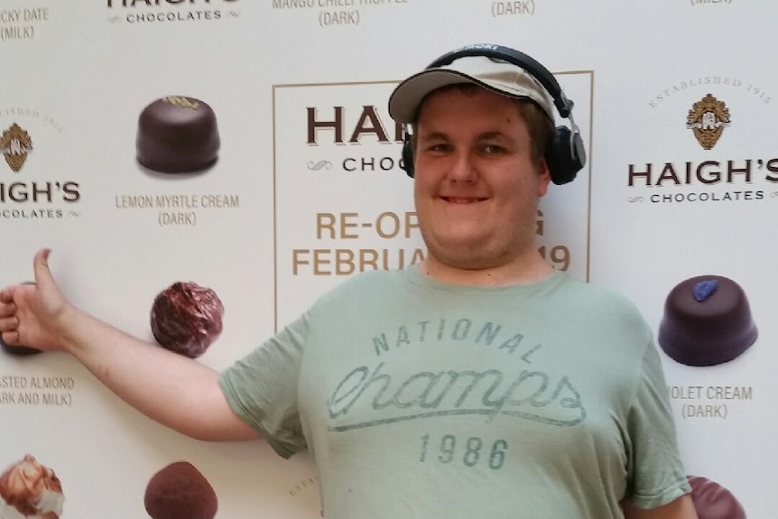 A man smiles in front of a sign for chocolates
