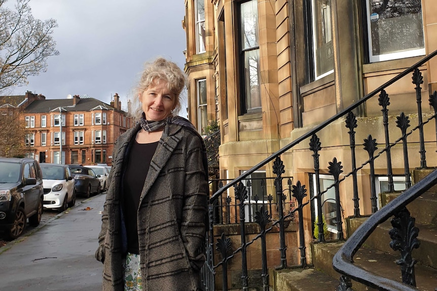 ABC reporter Claire Moodie standing in a Glasgow street among tenement buildings.