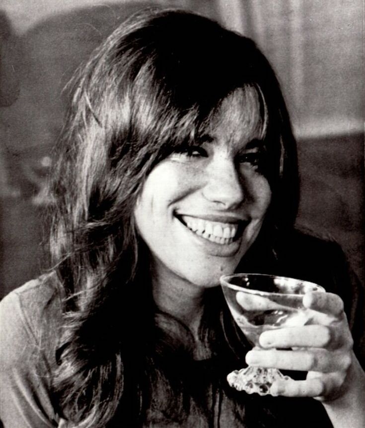 A young smiling woman salutes the camera with a glass