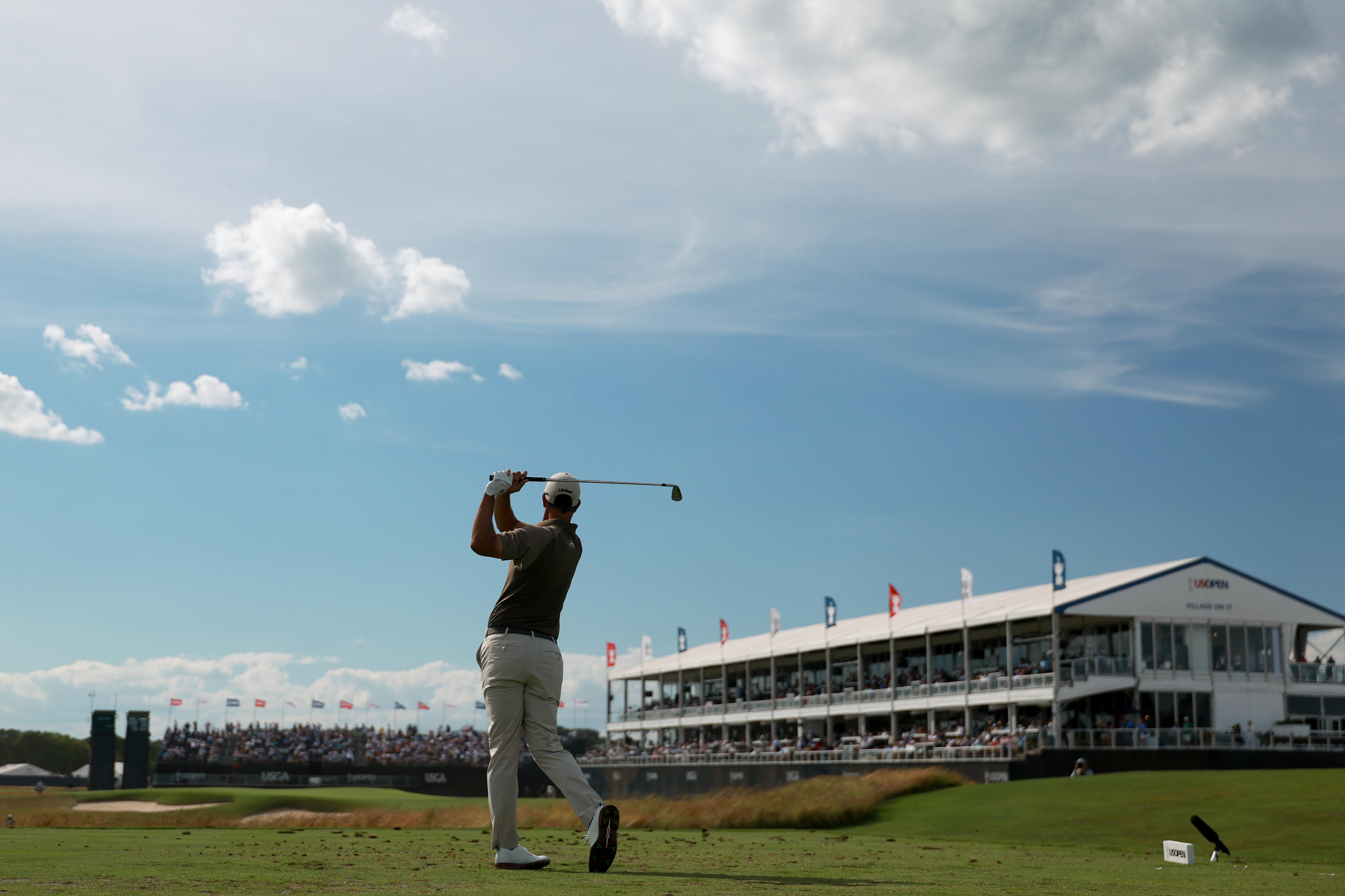A wide shot from behind of a golfer hitting a tee shot.