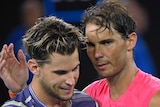 Two male tennis players embrace at the net at the completion of a tennis match at the Australian Open.