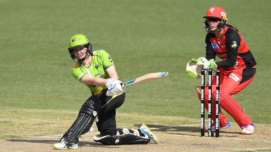 Alex Blackwell wears a yellow shirt and black trousers and plays a slog sweep shot with a cricket bat