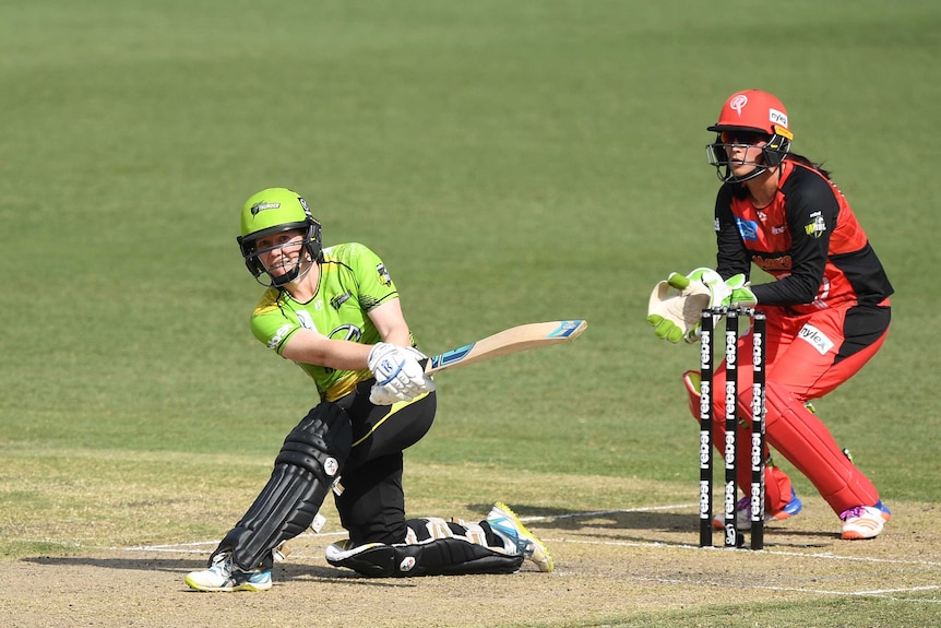 Alex Blackwell wears a yellow shirt and black trousers and plays a slog sweep shot with a cricket bat