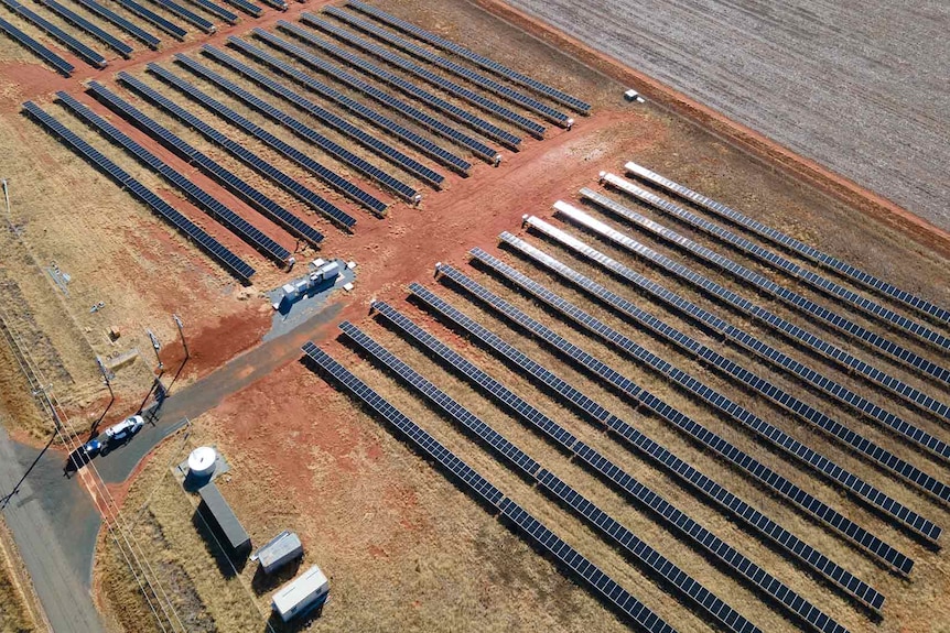 A birds-eye view of a solar filed with solar panels in a countryside