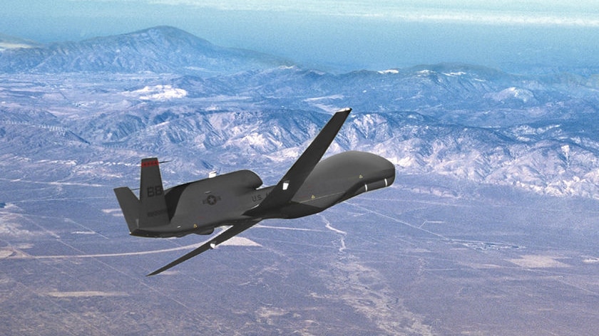 A Global Hawk drone made by Northrop Grumman flies above mountains.