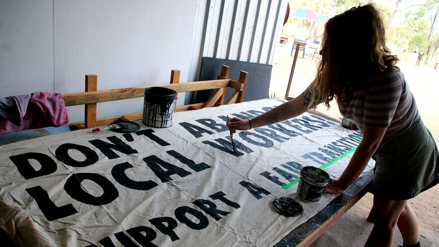 A woman paints a sign at the anti-Adani protest camp near Bowen.