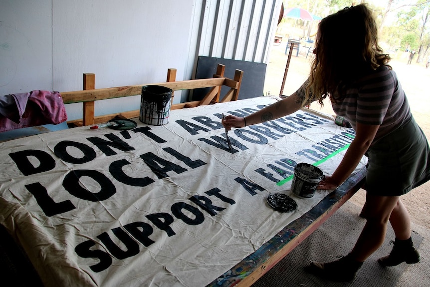 A woman paints a sign