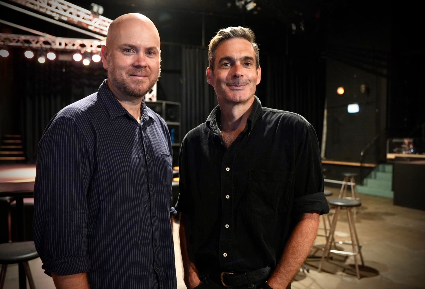 John y Dave posan para una foto con camisetas oscuras en un teatro musical.