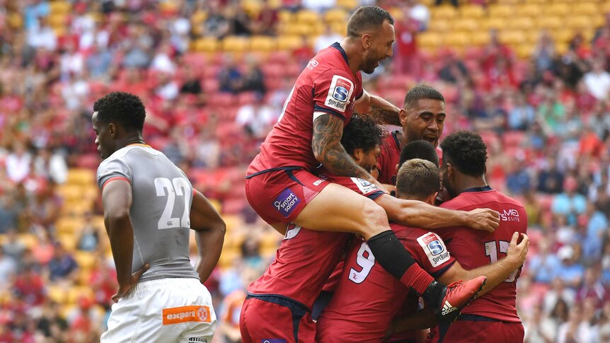Quade Cooper jumps onto the Queensland Reds' celebrating pack