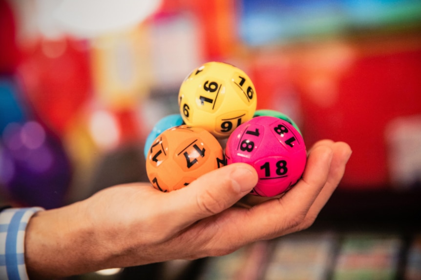 A man holds five lotto balls in his hands.