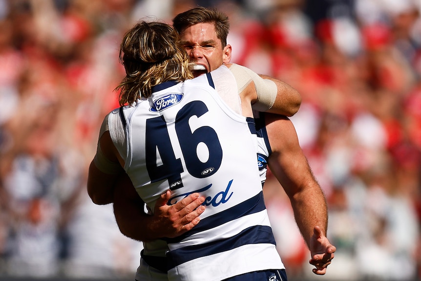 Tom Hawkins and Mark Blicavs embrace after a goal was kicked in the 2022 AFL grand final.