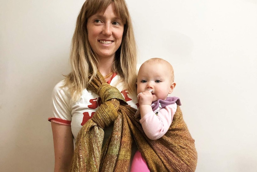 Woman holding a baby using an woven alpaca yarn baby wrap.