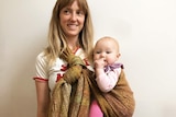 Woman holding a baby using an woven alpaca yarn baby wrap.
