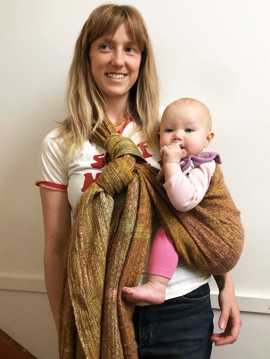 Woman holding a baby using an woven alpaca yarn baby wrap.