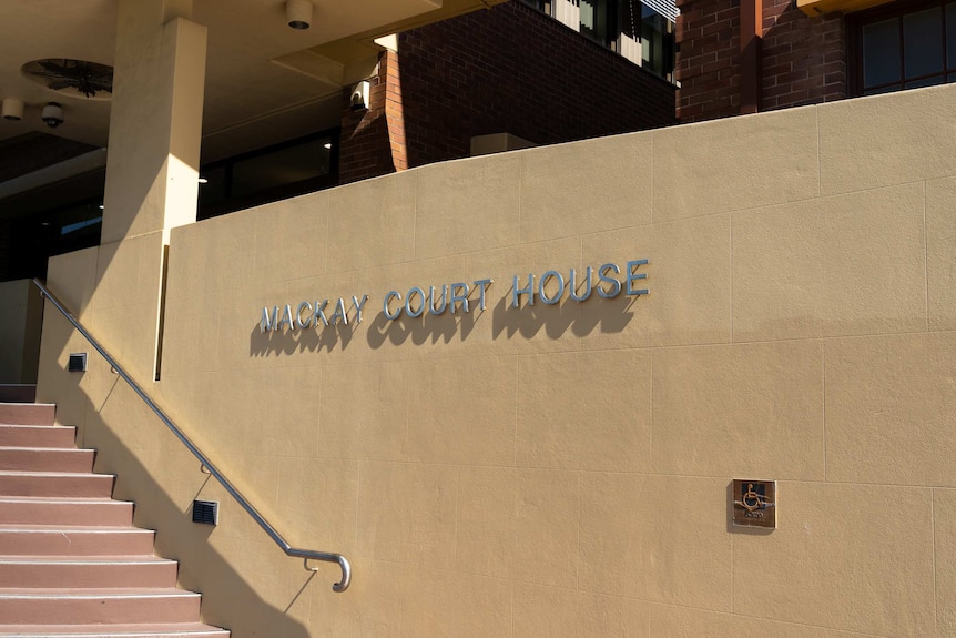 A set of steps next to a rendered brick wall with lettering that reads "Mackay Court House".