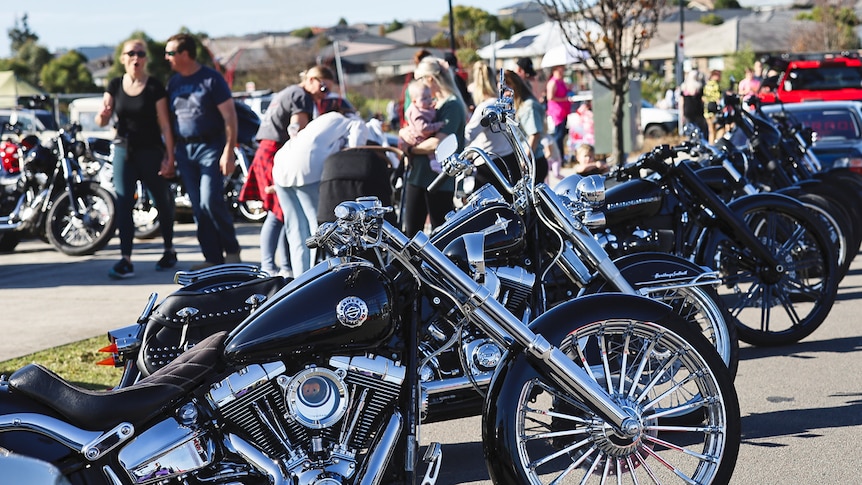 A row of motorcycles with people in the background.