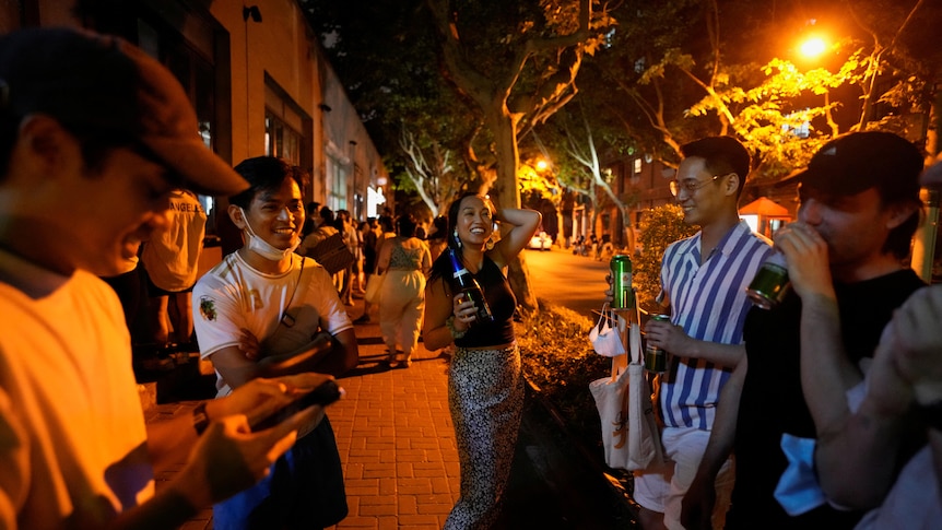 People drink on a street lit by street lights.