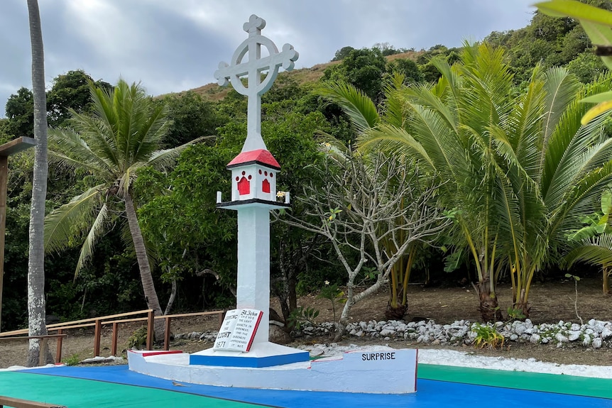 a monument in the shape of a white boat with the words surprise written on the side. Above the boat is a religious cross. Palm. 