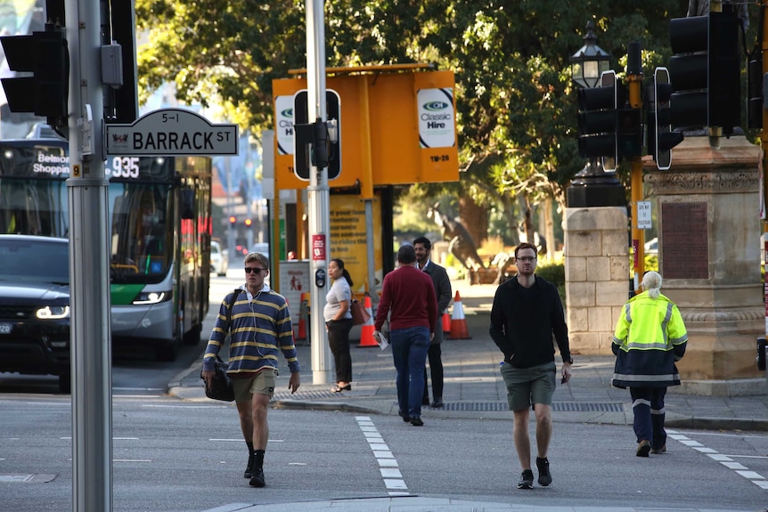A number of pedestrians cross the intersection of Barrack St in Perth on a cold April morning