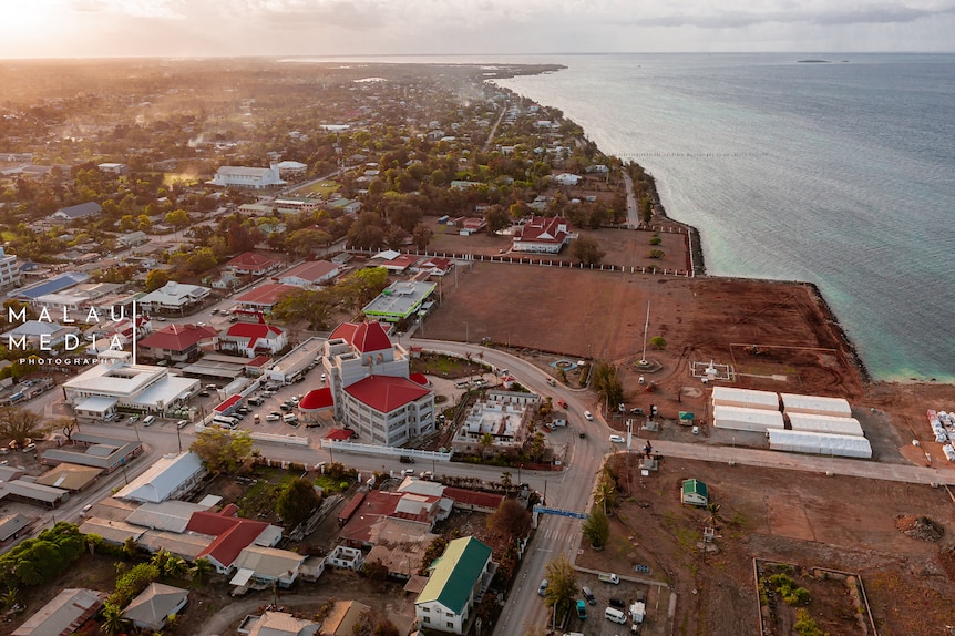Arial image of buildings by the ocean in Tonga, as sunsets. 
