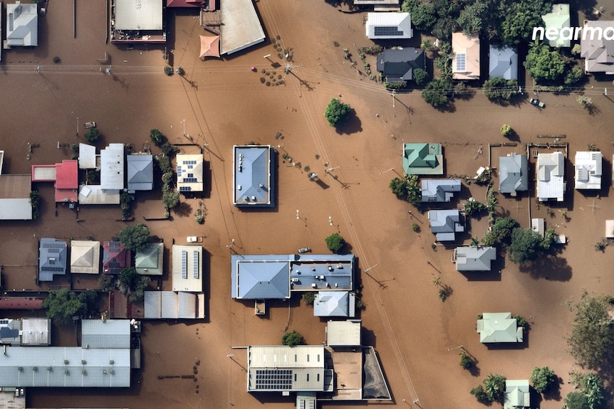 An aerial view of houses and commercial buildings in the middle of Lismore, totally surrounded by floods.