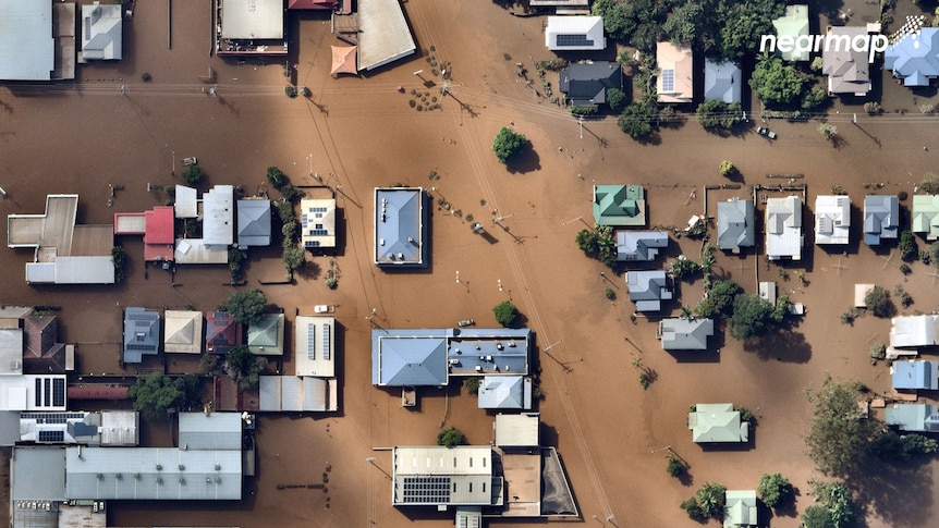 An aerial view of houses and commercial buildings in the middle of Lismore, totally surrounded by floods.