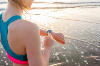 A woman looks at a fitness tracker on her wrist.