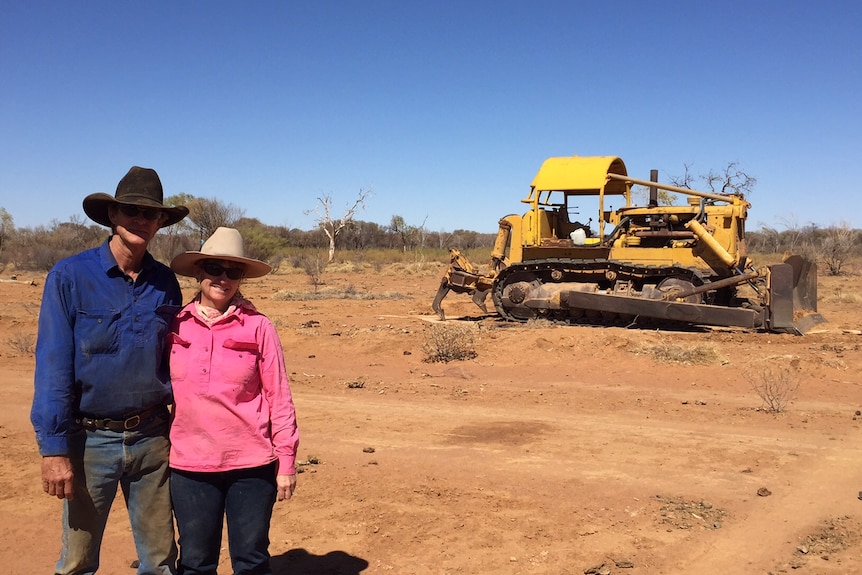 Peter and Cathy White in front of the bulldozer they use to push mulga to feed cattle