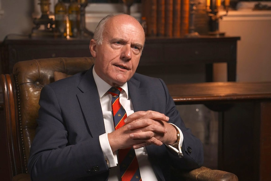 A man sitting in a chair wearing a suit and tie.