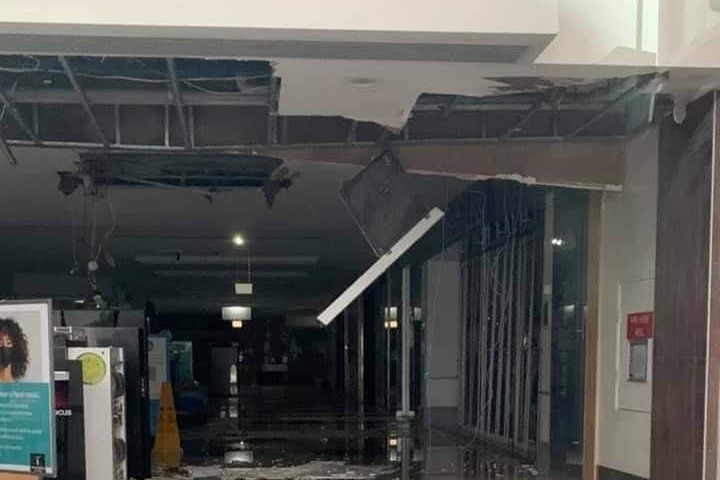 The roof of a shopping centre falling in, with debris on the ground.